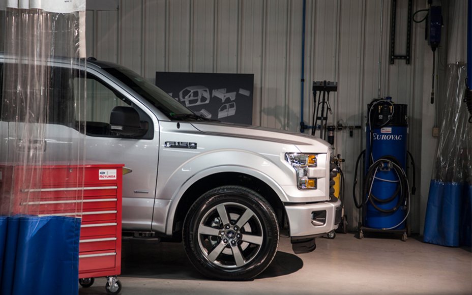 F-150 truck sitting in a body shop surrounded by machinery